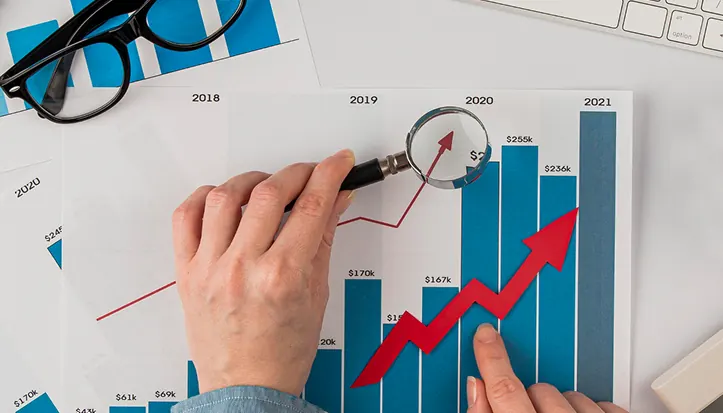 Rising bar chart under a magnifying glass
